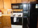 Kitchen of Alpine Snow Cabin. Featuring stove, refrigerator, microwave, small appliances, and cookware.